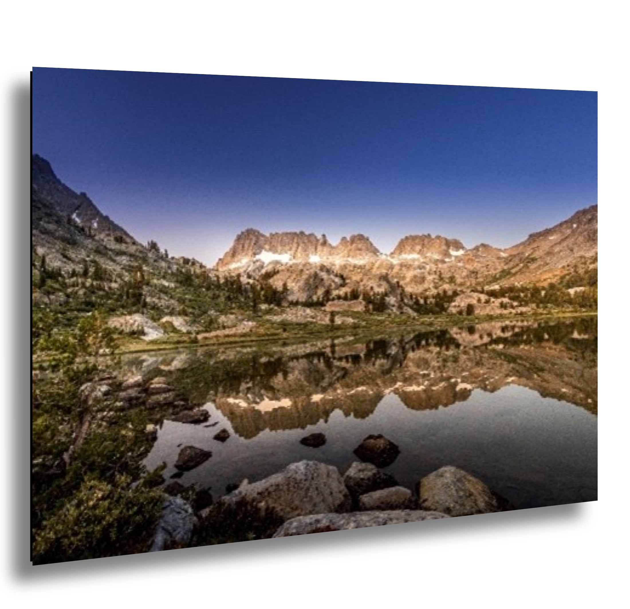 Mountain lake reflection with granite peaks, alpine forest, and clear blue sky landscape photography.