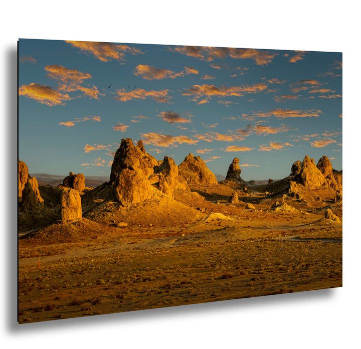 Trona Pinnacles tufa formations at golden hour with orange clouds and blue desert sky.