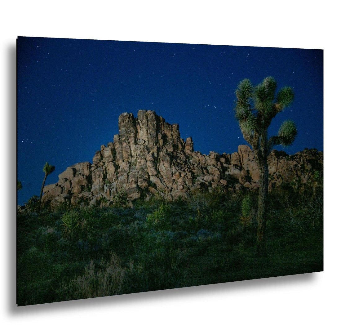 Joshua Tree night photography with rock formations under starry blue desert sky.