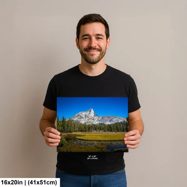 Man smiling and holding a 16x20 inch print of a mountain landscape with clear blue skies and lush greenery.