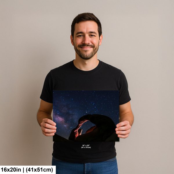 Photographer holding 16x20 inch Mobius Arch Milky Way print on neutral background.