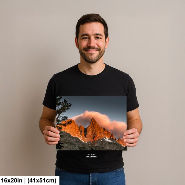 Man holding a 16x20 inch print of a mountain landscape with golden light and clouds, smiling against a neutral background.