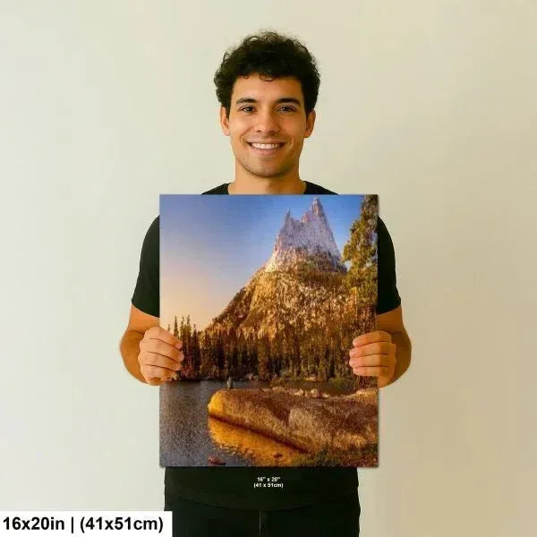 Man smiling and holding a 16x20 inch print of a beautiful mountain scene with a reflection in a peaceful lake surrounded by trees.