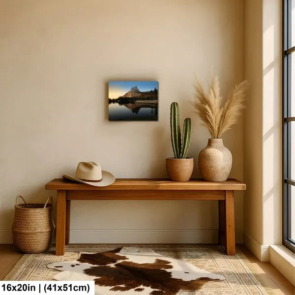 Modern entryway with a wooden bench, cowhide rug, and potted plants, featuring a mountain landscape print on the wall with warm natural light.