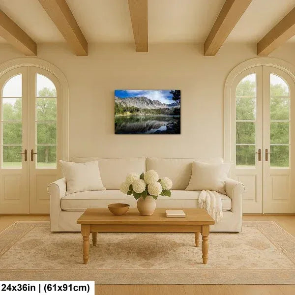Alpine lake reflection landscape canvas above cream sofa in bright farmhouse living room with arched doors.