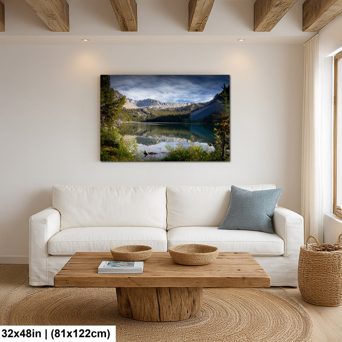 Alpine lake reflection with granite mountains and forest canvas above white sofa in modern farmhouse living room.