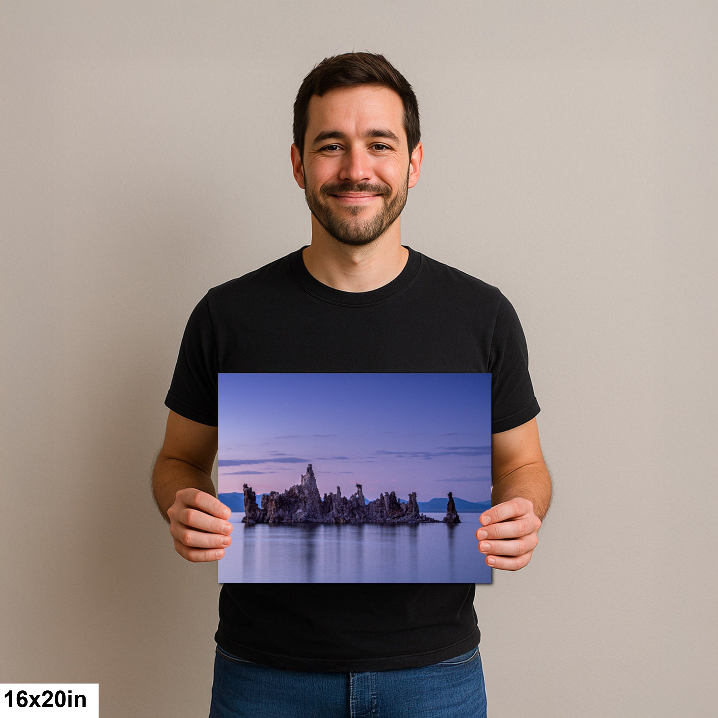 Man holding a 16x20 inch print of rock formations in the water, bathed in soft purple light under a tranquil twilight sky.