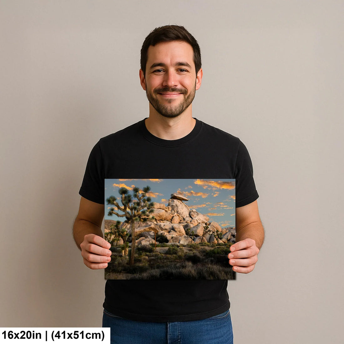 Man holding Joshua Tree boulders and desert landscape sunset photography canvas print with golden hour sky.